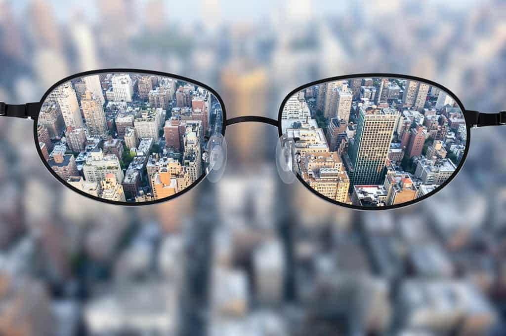 Clear cityscape focused in glasses lenses with blurred cityscape background